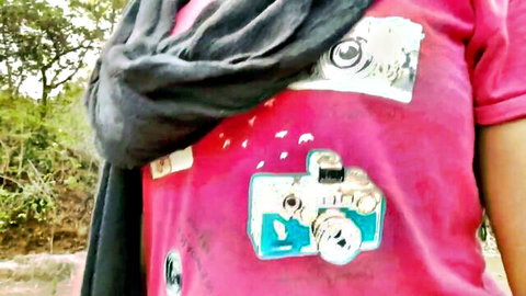Mumbai Ashu in pink camera-print top and gray scarf outdoors in Indian village