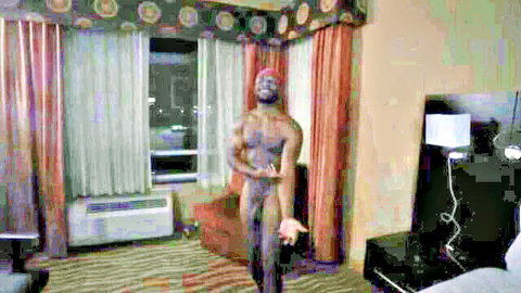 Nude muscular ebony man flexing in hotel room pose