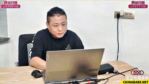 Asian man in black t-shirt working on laptop