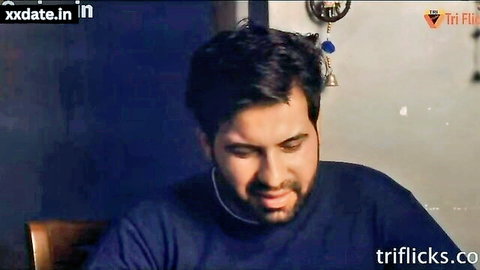 Handsome bearded man in blue shirt sitting indoors with intense expression