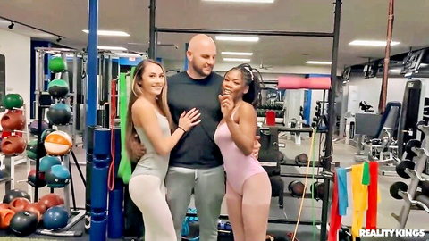 Fit blonde and ebony gym babes in tight outfits pose with muscular stud in Reality Kings scene