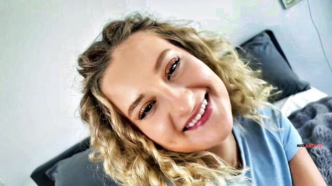 Miley Summer smiling with curly blonde hair in blue top