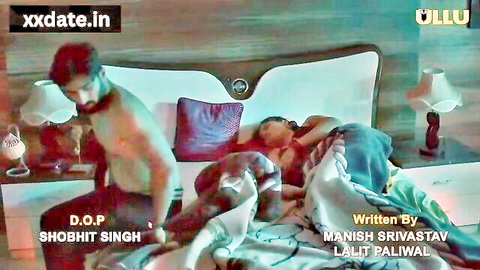 Shirtless bearded Indian man leans over woman covered by sheet in steamy bed tease