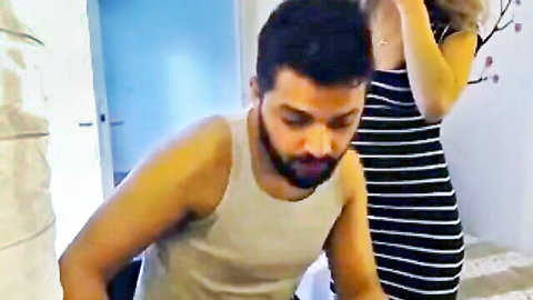 Bearded Arab man in tank top kneels behind blonde in tight striped dress groping her ass