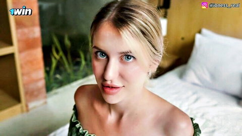 Mila Lioness in off-shoulder green top, blonde hair, seductive blue-eyed gaze