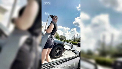 Sexy teen in tight shorts and tank top leaning over car door outdoors with mic stand