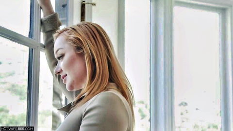 Sexy redhead leaning against window in tight beige jacket teasing her curves