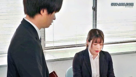 Asian female boss in office attire with male subordinate standing behind her