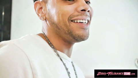 Smiling handsome biracial man with beard, earrings and chain necklace in white shirt