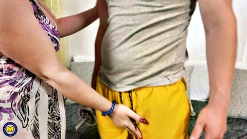 Mature woman in purple dress handles young Rick Palmer's arm teasingly