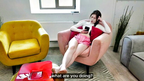 Asian teen in pink shorts and white top lounging relaxed, holding phone