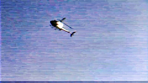 Black helicopter soaring upwards against clear blue sky