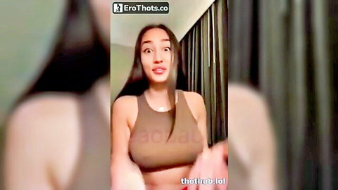 Asian beauty in low-cut brown tank top teasing with deep cleavage