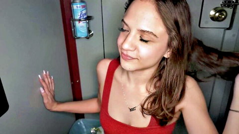Callie Klein in red tank top smiling at gloryhole booth