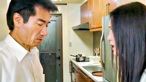 Mature Japanese man in white shirt stares intensely at young Asian woman with long black hair in kitchen