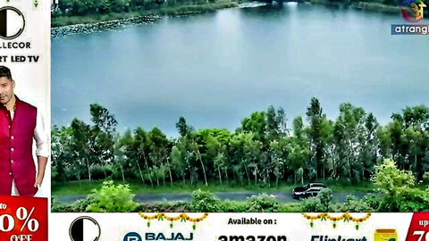 Indian man in maroon kurta by scenic lake with trees and promo banners