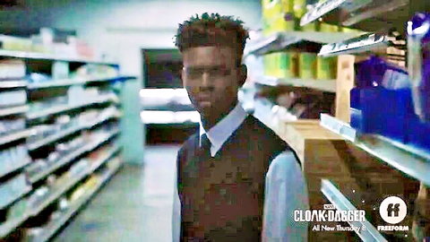 Young Black man with afro hair in vest and shirt standing in store aisle