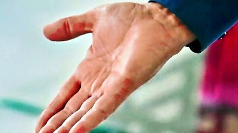 Man's hand extended palm up in blue sleeve, teasing adult video scene