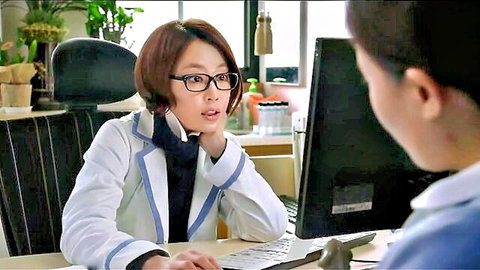 Asian doctor in glasses and lab coat at desk in office tease