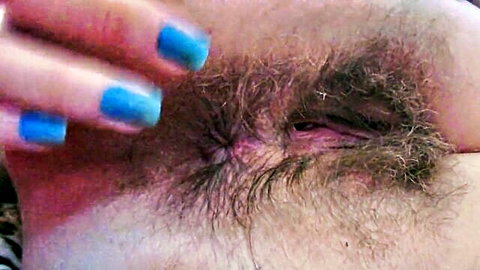 Woman's blue nailed fingers pulling thick bushy hairy eyebrow closeup