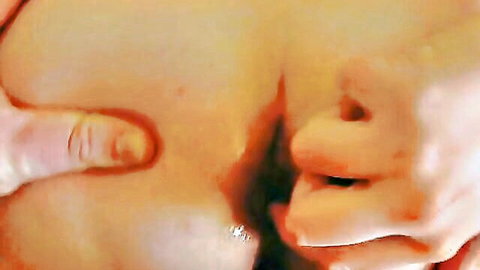 Hand spreading woman's hairy ass cheeks wide exposing pink anus closeup