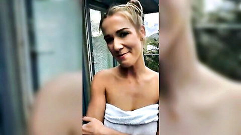 Blonde beauty in white towel on sunny balcony, teasing smile