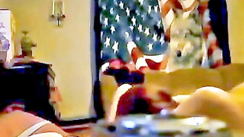 Blurry amateur babes in colorful dresses lounging on couch near American flag curtain