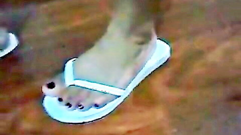 Sexy Latin feet in white flip flops, dark pedicure closeup