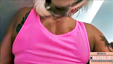 Tattooed blonde woman in pink tank top, cleavage tease after party