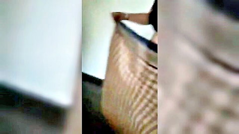 Blurry closeup of hand gripping woven beige basket against wall