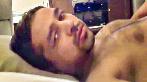 Hairy chested mature Indian man lying shirtless on couch with seductive gaze