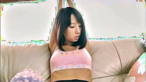 Skinny Japanese girl with small tits stretches arms overhead in pink bra on couch