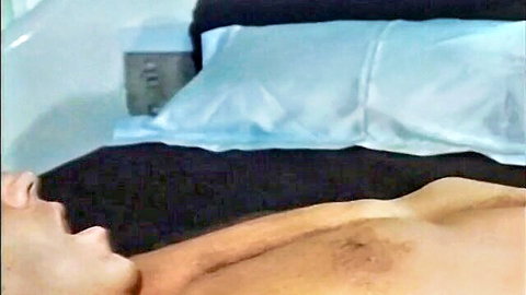 Naked man moaning in ecstasy with hairy chest and pubes on black bed sheets
