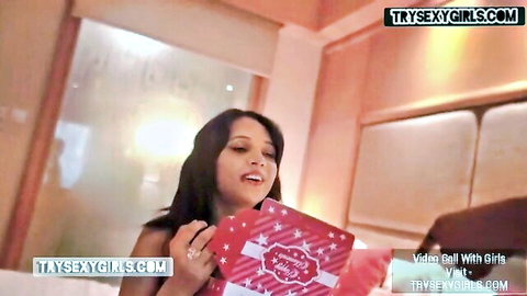 Smiling Indian girlfriend with cleavage holding red gift box