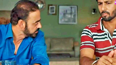 Two bearded Indian men in shirts gesturing while talking on living room couch