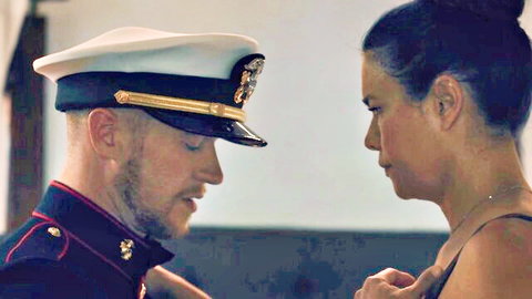 Navy officer in uniform stares intensely into sexy brunette's eyes in close intimate moment