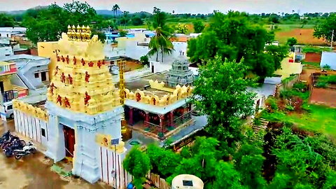 Aerial view of traditional Indian temple with golden spires and lush surroundings