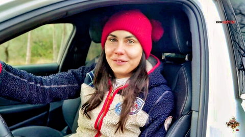 Jenny Stella in scout jacket smiling from car window, red beanie