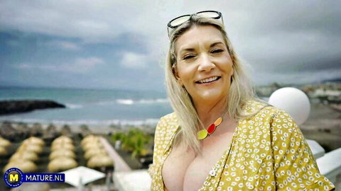 Mature blonde mommy in yellow dress shows big tits and booty on beach solo