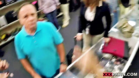 Blurry pawn shop scene with surprised bald man in blue shirt and brunette woman in blazer holding red folder