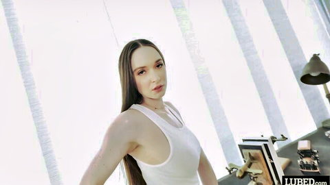 Hazel Moore in white tank top, seductive lean on desk, long dark hair