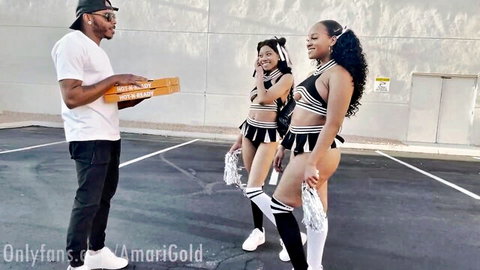Musa Phoenix with two busty black cheerleaders in skimpy outfits by pizza box