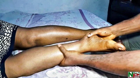 Ebony mature woman gets sensual foot and leg massage with legs spread on bed