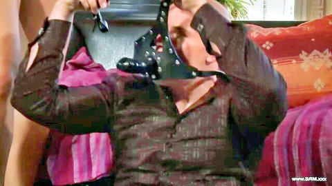 Man holds black leather BDSM mask with huge dildo gag for fetish play