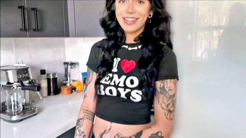 Tattooed emo babe smiling in tight I heart emo boys crop top showing midriff in kitchen