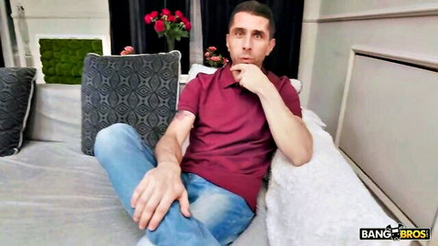 Handsome Bang Bros stud in maroon polo shirt pondering on couch with hand on chin