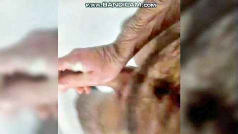 Blurry close-up of wrinkled hands holding white fluid in amateur adult scene