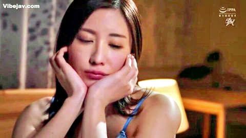 Cute Japanese housewife pouting seductively framing face with hands in blue top