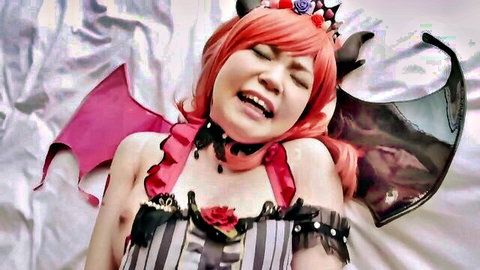 Pink-haired Japanese cosplay demon girl with horns and wings moaning in ecstasy, cleavage spilling from frilly lingerie