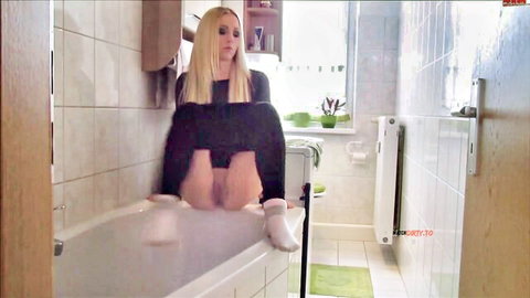 Blonde Lucy Cat teasing in bathtub, black dress hiked up, white socks